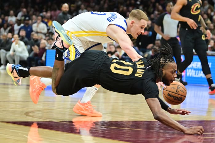 Jan 20, 2023; Cleveland, Ohio, USA; Cleveland Cavaliers guard Darius Garland (10) is tripped up by Golden State Warriors guard Donte DiVincenzo (0) during the second half at Rocket Mortgage FieldHouse. Mandatory Credit: Ken Blaze-USA TODAY Sports